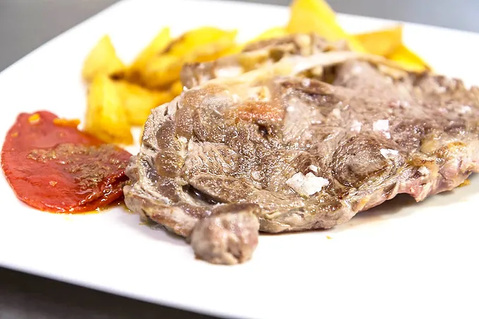 Plato de chuleta con guarnición de patatas servido en uno de los restaurantes Ñam.